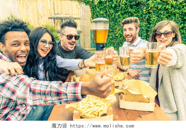 一群多民族朋友在喝啤酒杯快乐的人聚会和在家庭花园吃饭
